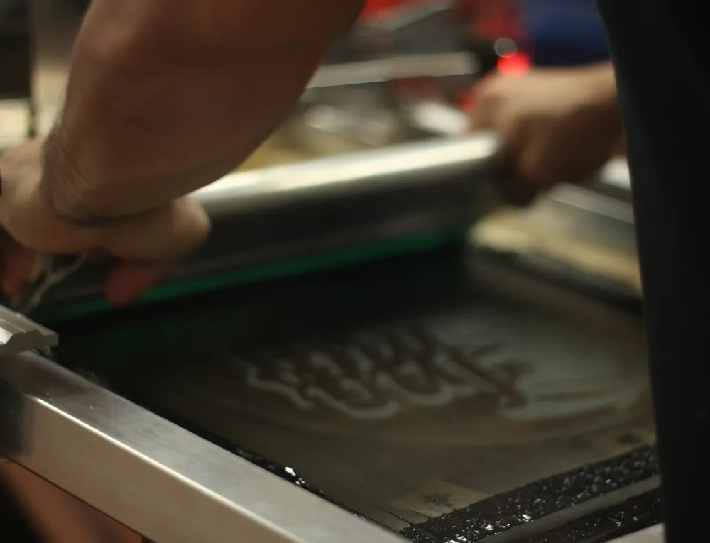 Pulling a screen print by hand in the shop